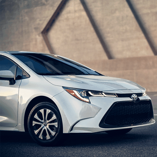 Everything You Need to Know about Your Car Battery at Lancaster Toyota | Close Up of 2022 Toyota Carolla Hybrid Driving in Front of Stone Wall Facing Right