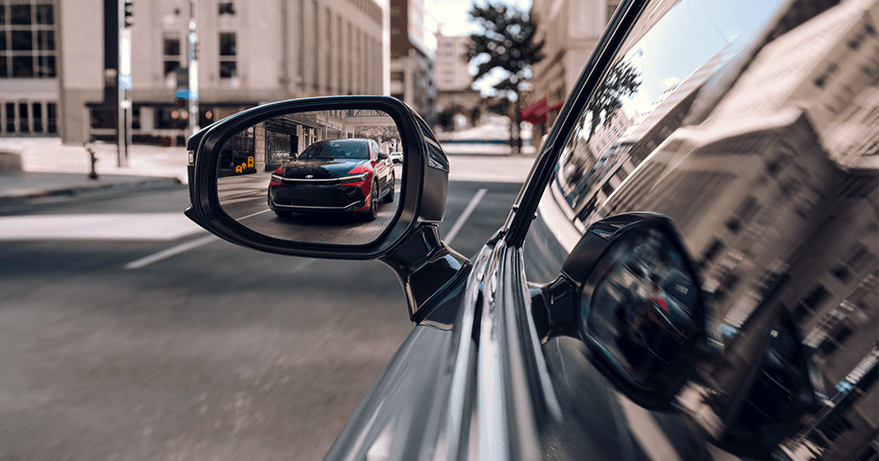 2023 Toyota Crown at Lancaster Toyota in East Petersburg, PA | Exterior view of a drivers side mirror with the reflection of a red 2023 Toyota Crown driving down the street