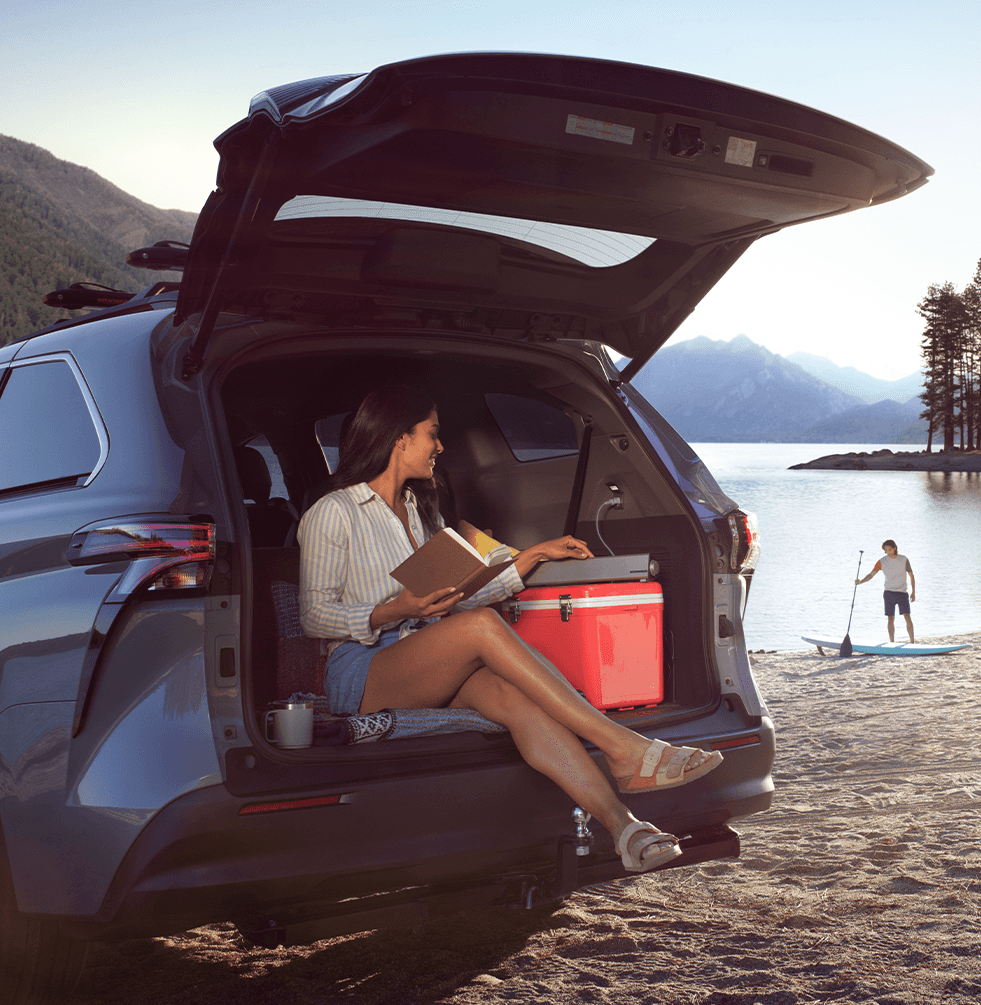 The New 2023 Toyota Sienna at Lancaster Toyota in East Petersburg, PA | Woman sitting in the back of a Toyota Sienna trunk while reading a book