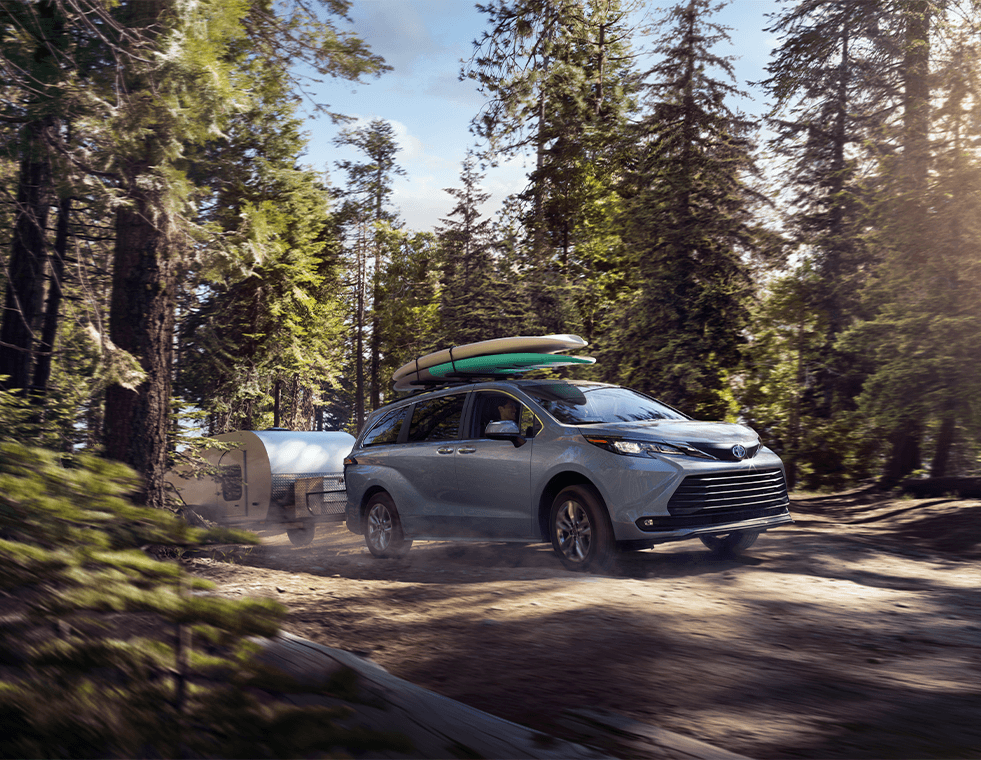 The New 2023 Toyota Sienna at Lancaster Toyota in East Petersburg, PA | 2023 Toyota Sienna driving through the wood towing a trailer in the back