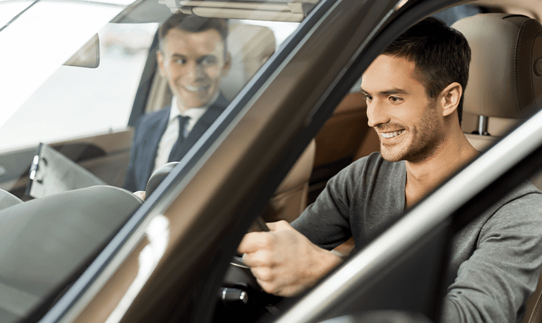 Enjoy A Test Drive At Lancaster Toyota in East Petersburg, PA | Happy man sitting in a new car while a sales person is sitting next to him in the passenger seat