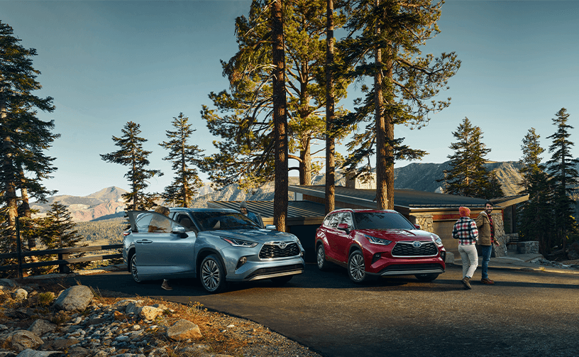2023 Toyota Highlander at Lancaster Toyota in East Petersburg, PA | Two 2023 Toyota Highlander parked beside each other in front of driveway and in the background are trees and mountains
