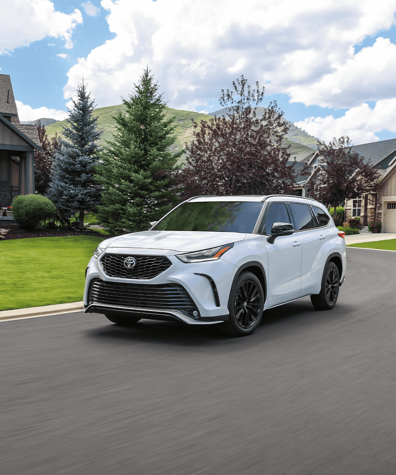 2023 Toyota Highlander at Lancaster Toyota in East Petersburg, PA | Front view of a white 2023 Toyota Highlander driving past a neighborhood