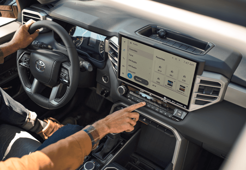 2023 Tundra vs 2023 Tacoma at Lancaster Toyota | Black interior of a Toyota Tundra with touchscreen while a man has his hands on the steering wheel