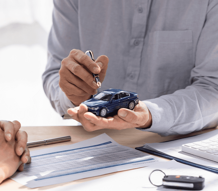 Defining GAP Insurance at Lancaster Toyota in East Petersburg, PA | Sales person explaining what GAP insurance is by holding a miniature car in hand