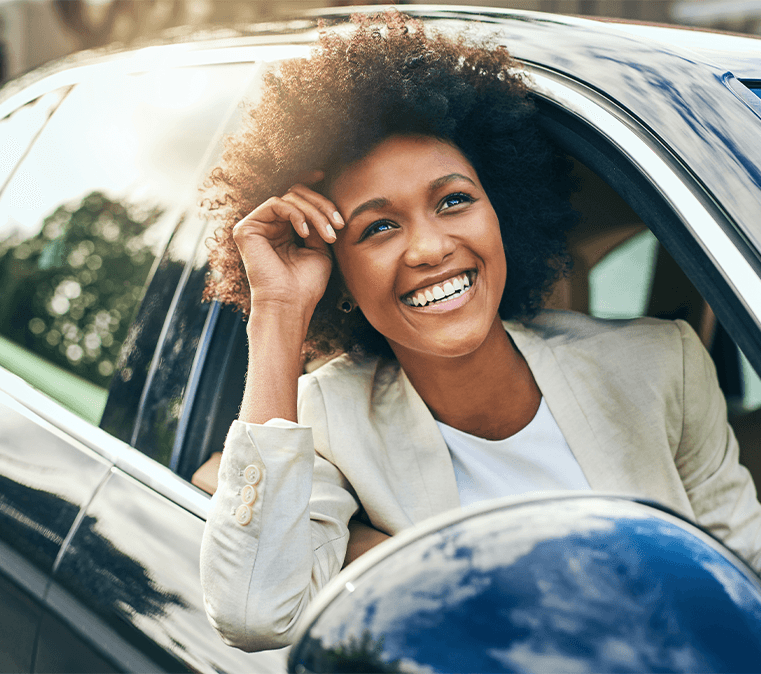 Defining GAP Insurance at Lancaster Toyota in East Petersburg, PA | Woman smiling and enjoying the nice day by the passenger side of the car