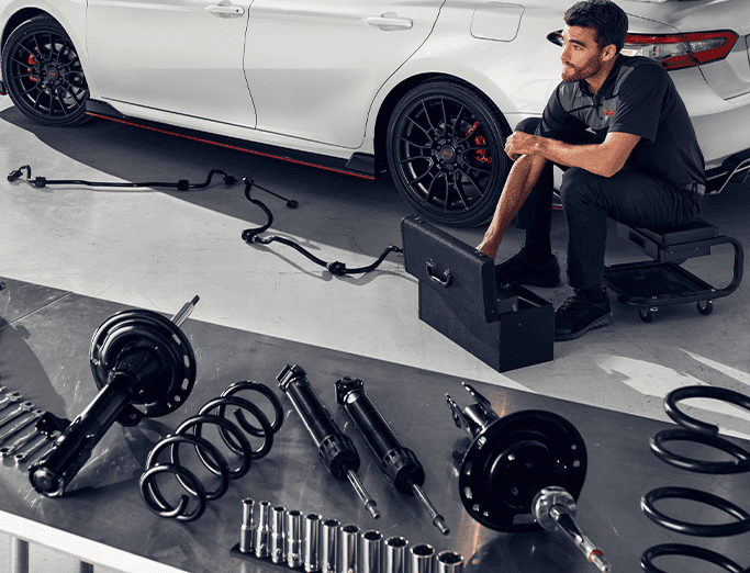Why you should avoid potholes in East Petersburg, PA | Table with suspension parts while a mechanic is sitting down near a white Toyota