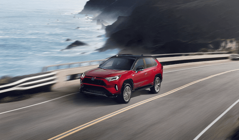 Most Fuel Efficient Toyota Models at CMA's Toyota of Martinsburg | Red Toyota RAV4 driving down a road while driving past an ocean view