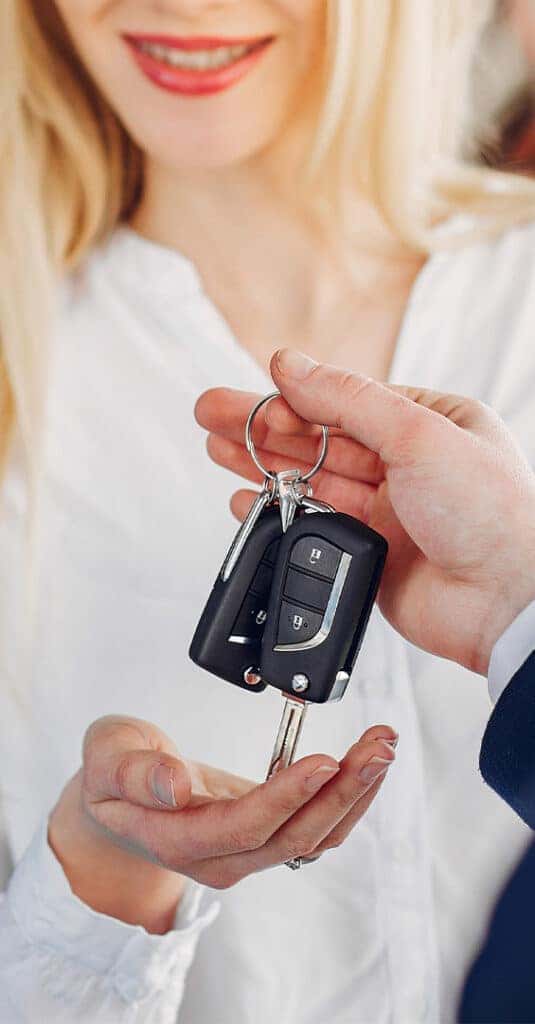 High Cost of Replacing a Car Key | Lancaster Toyota | Person pasing new car keys to a woman in white shirt 