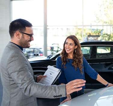 Vehicle Registration Taxes and Fees at Lancaster Toyota in East Petersburg, PA | Customer laughing and smiling while talking to sales associate inside of dealership