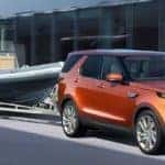 2019 Land Rover Discovery in orange towing a boat