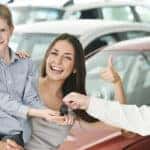 At automobile sales centre. Car salesperson selling new automobile to young family with child boy