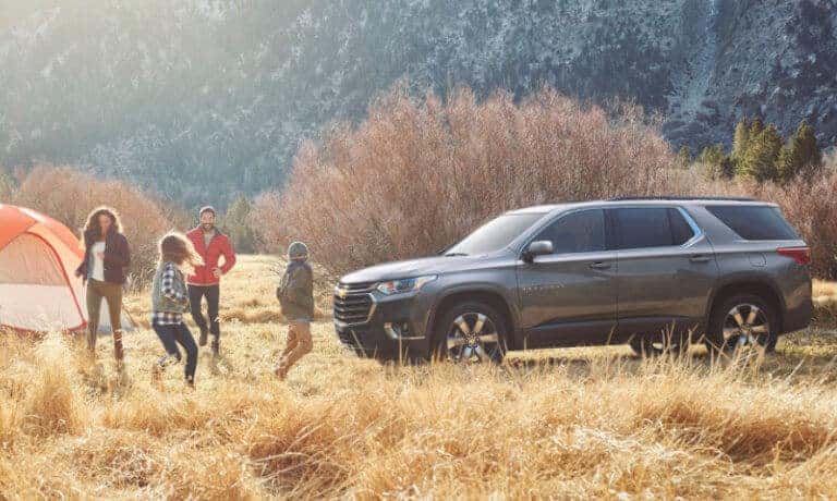 2020 Chevy Traverse in gray parked at camp site in the mountians with a family