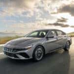A 2025 Hyundai Elantra is cruising along a scenic road, showcasing its sleek design and modern features.