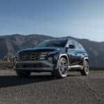 a blue 2025 tucson hybrid parked in front a sprawling mountainscape