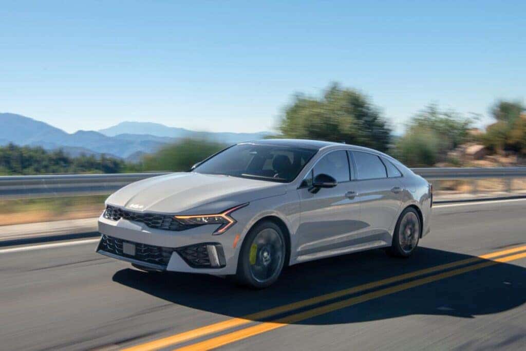 A 2025 Kia k4 cruising along a scenic road, showcasing its sleek design and modern features.