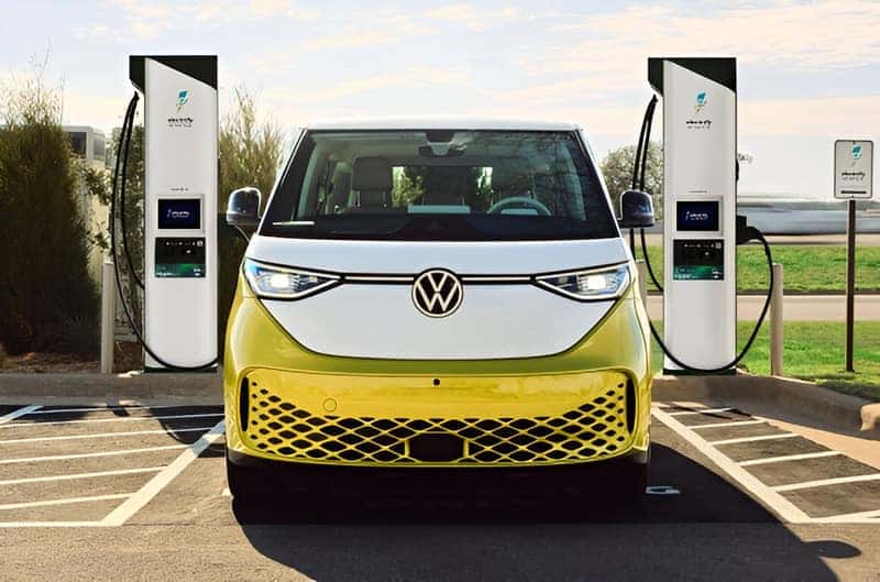 The 2025 VW ID.Buzz in Pomelo Yellow in front of Electrify America charging stations