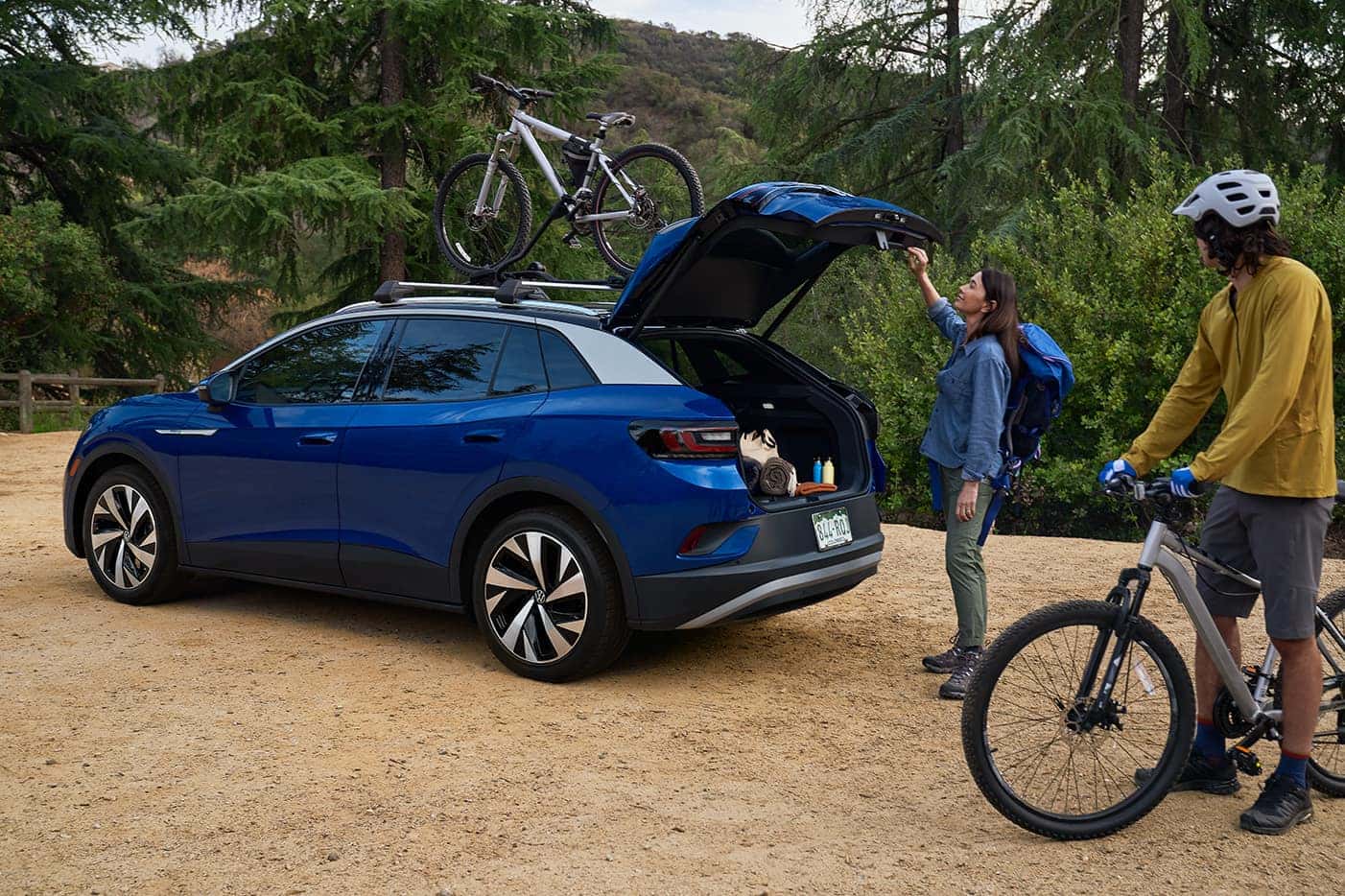 blue volkswagen id.4 ev suv two people bikes trees