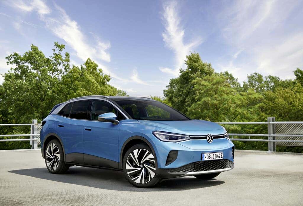 Blue Volkswagen ID.4 EV SUV Fence Green Trees