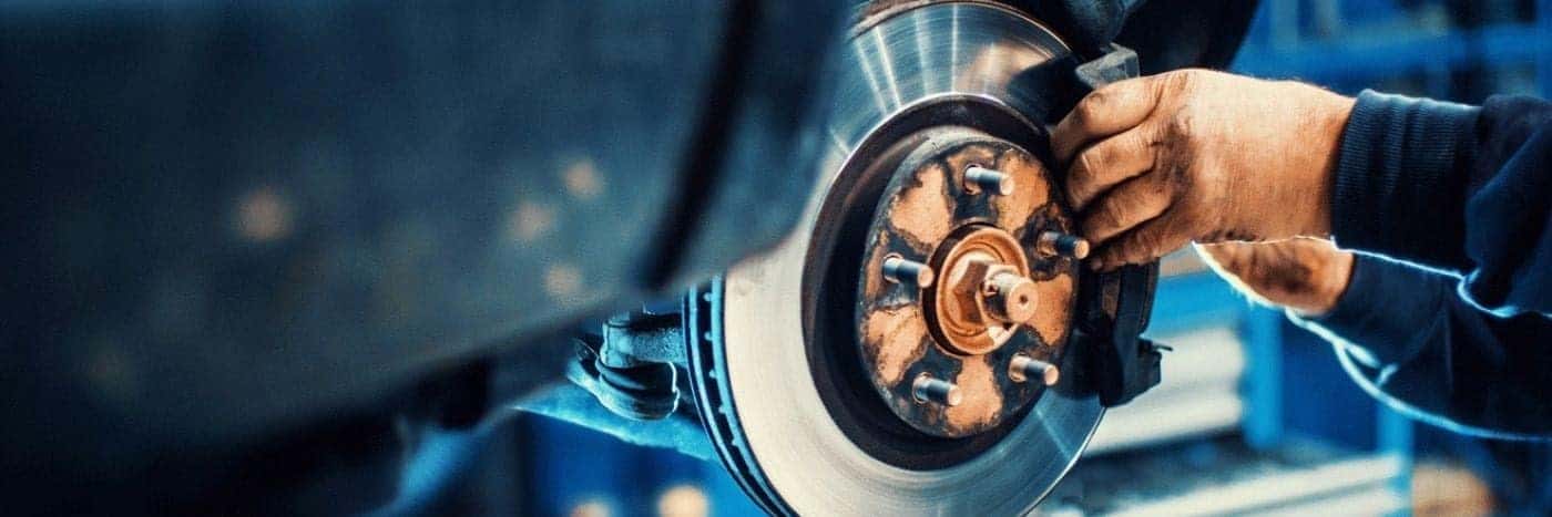 Close up view of a service tech inspecting a vehicle's brake rotor
