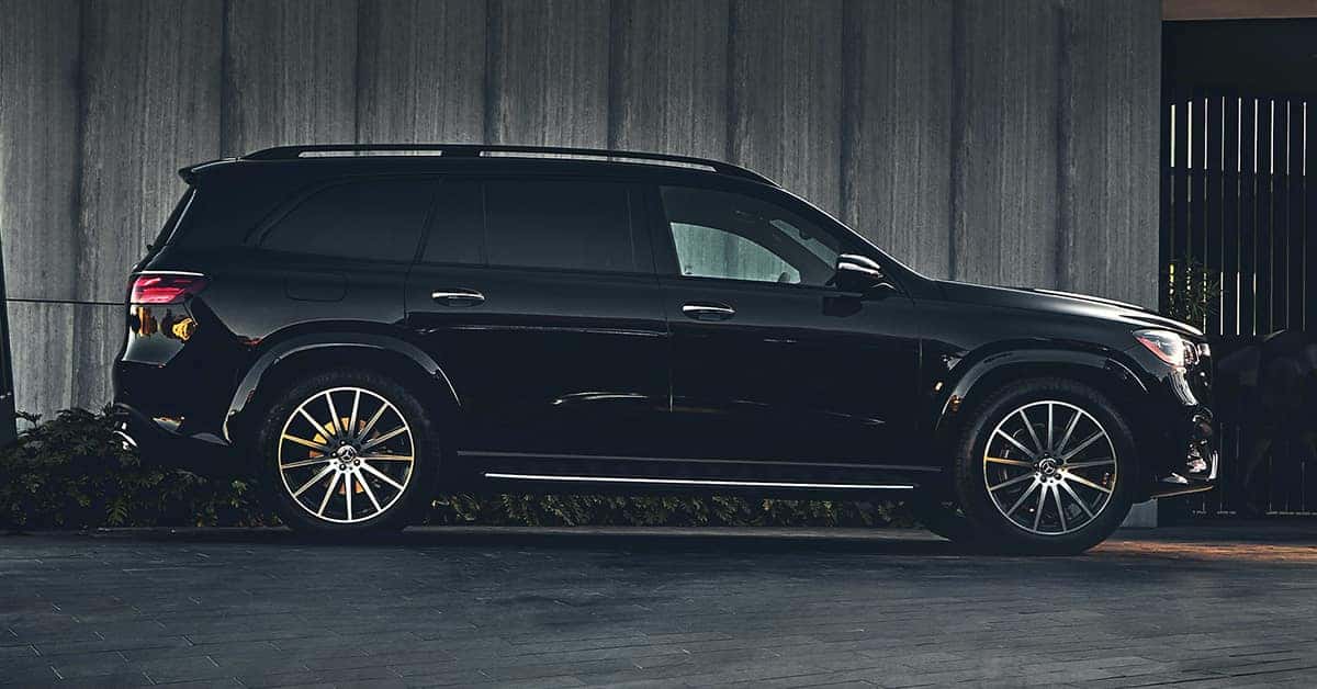 black 2026 Mercedes-Benz GLS SUV parked against a dark, textured concrete wall.