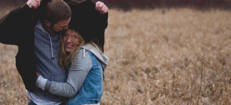 Woman Hugging Man in Brown Field